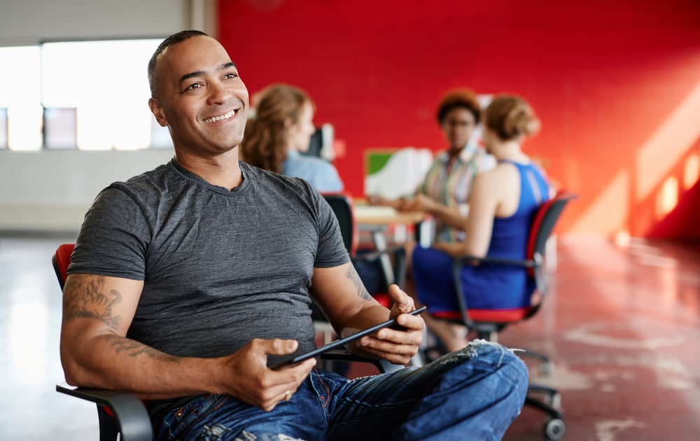 Confident male designer working on a digital tablet in red creative office space