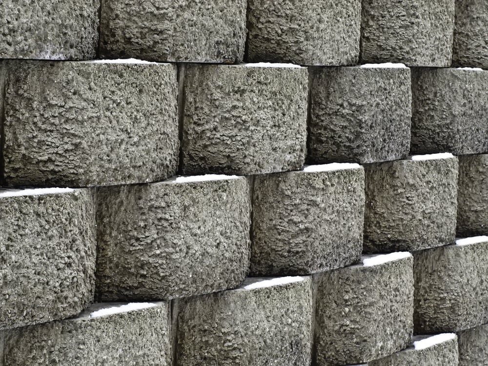 Wintry pattern of architecture and nature Retaining wall of textured concrete blocks with snow in the same spot on each